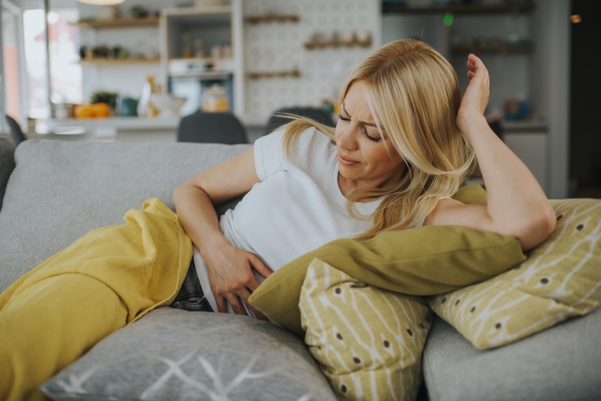 Woman with hands on stomach suffering from pain.