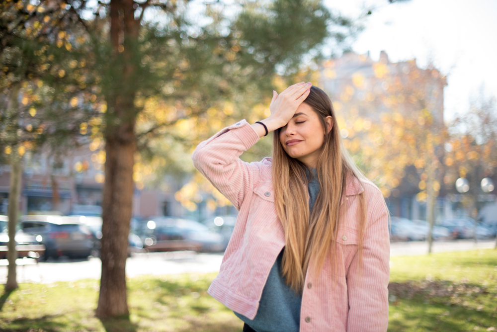 Young woman in park doing a face palm after a mistake, 