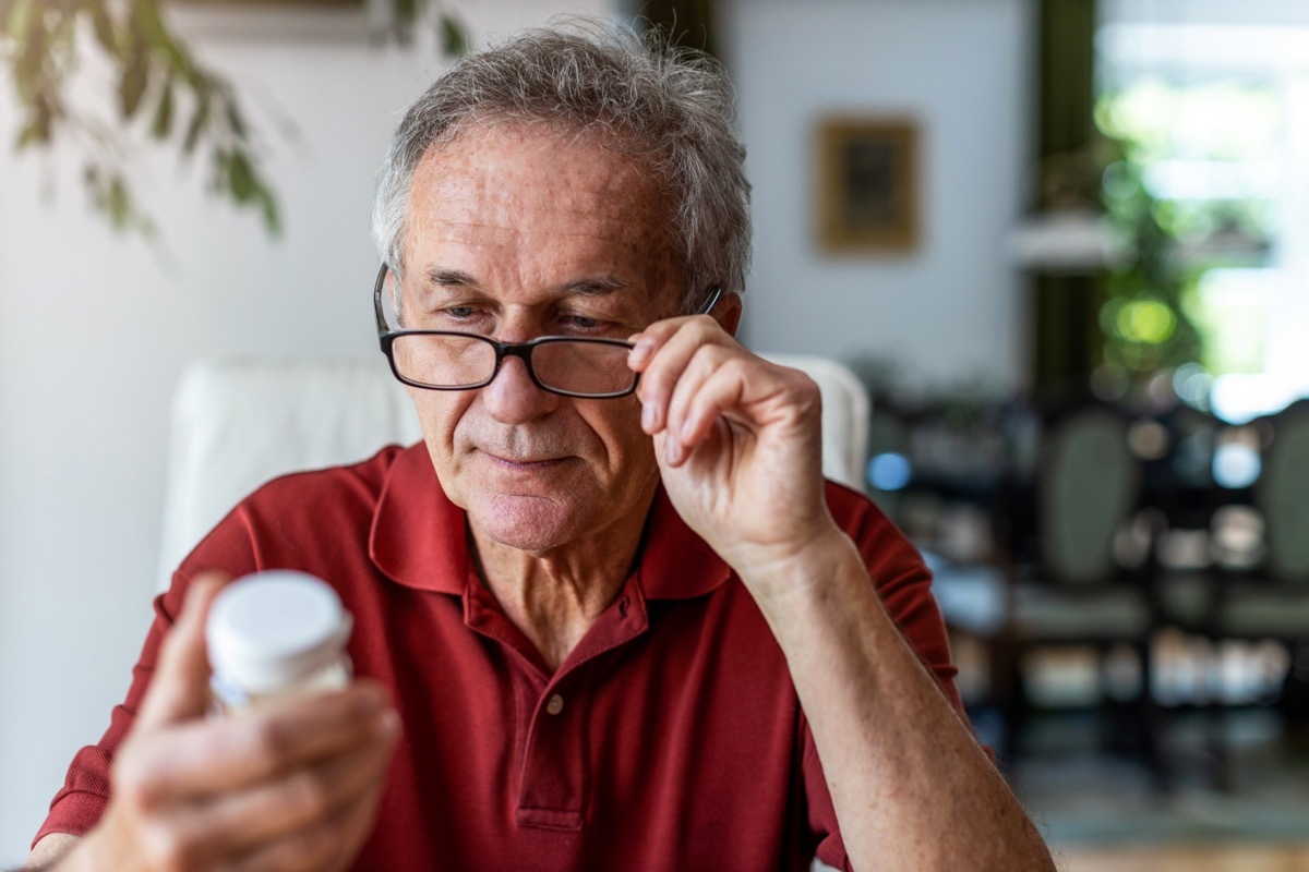 Senior man taking prescription medicine at home