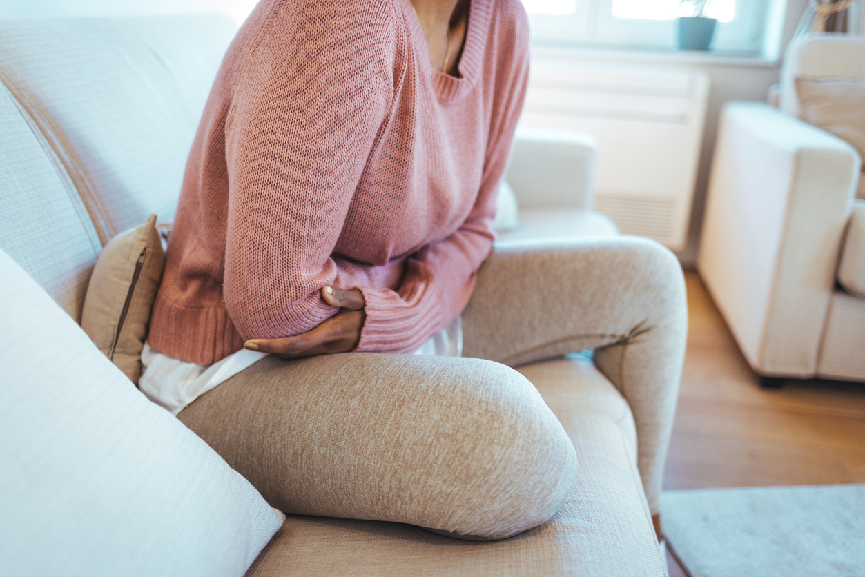 Woman sitting down holding her stomach.