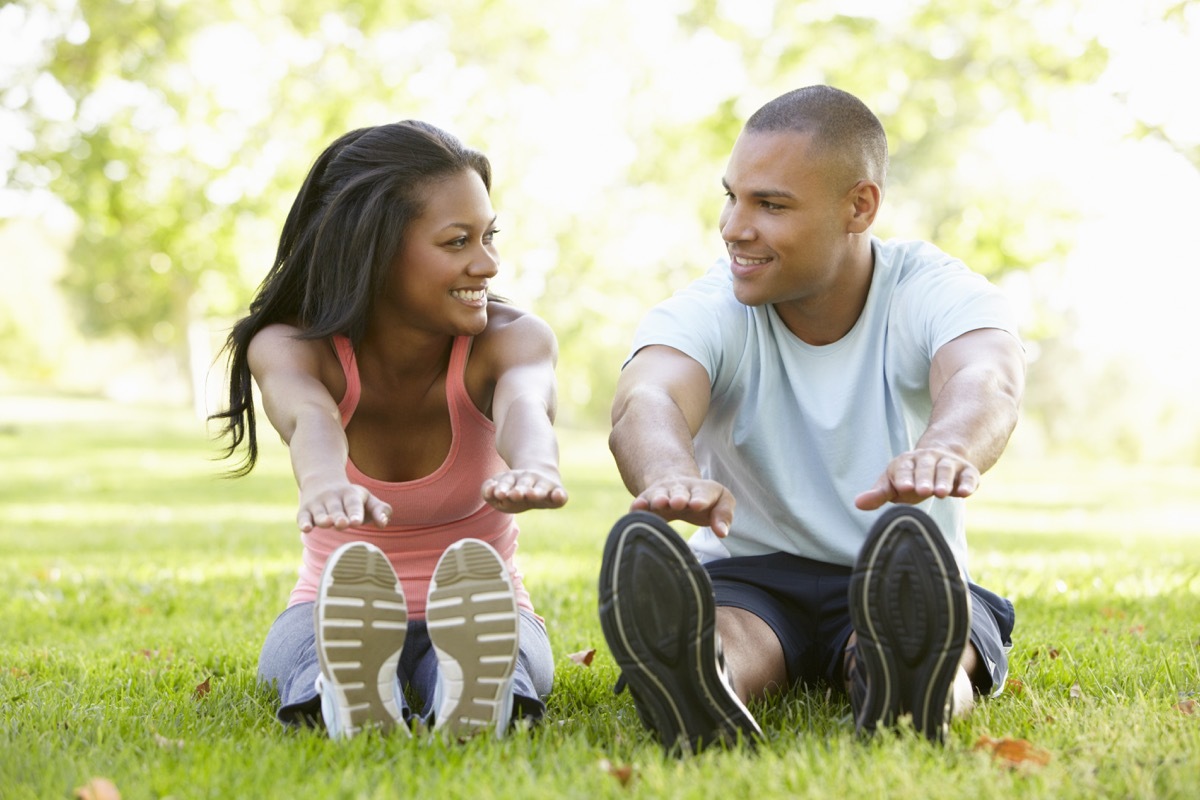 Young black couple stretching together in the gras