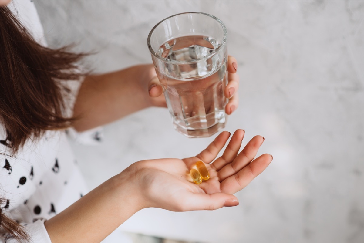 woman taking vitamin d supplement with water