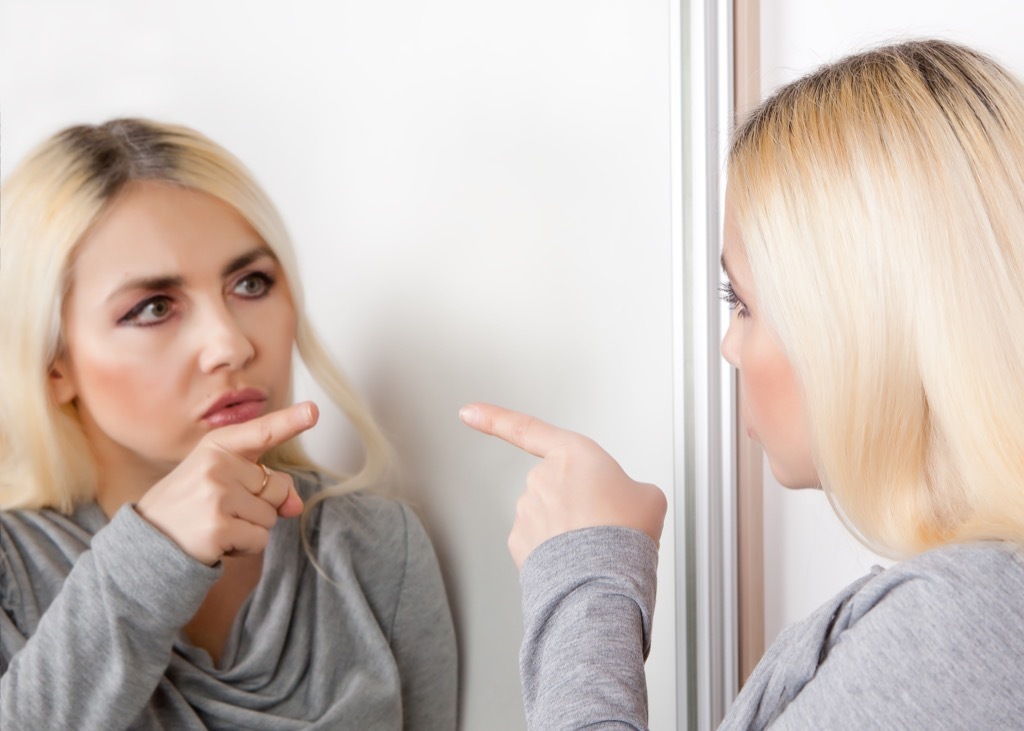 Woman yelling at herself in the mirror