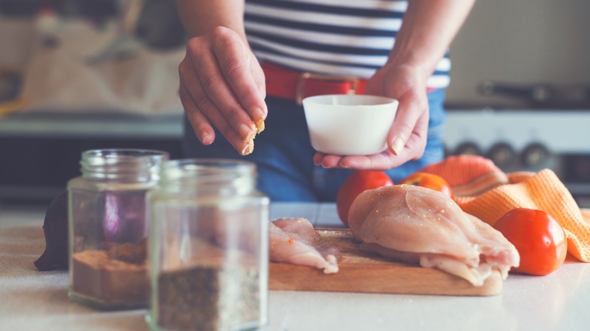 young woman preparing chicken meat