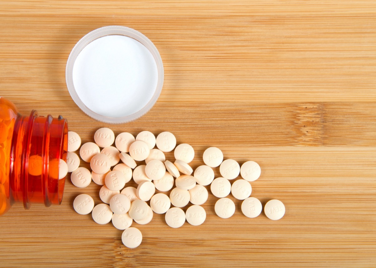 Top view flat lay 1 prescription bottle of Famotidine, generic for Pepcid, spilled on a wood table