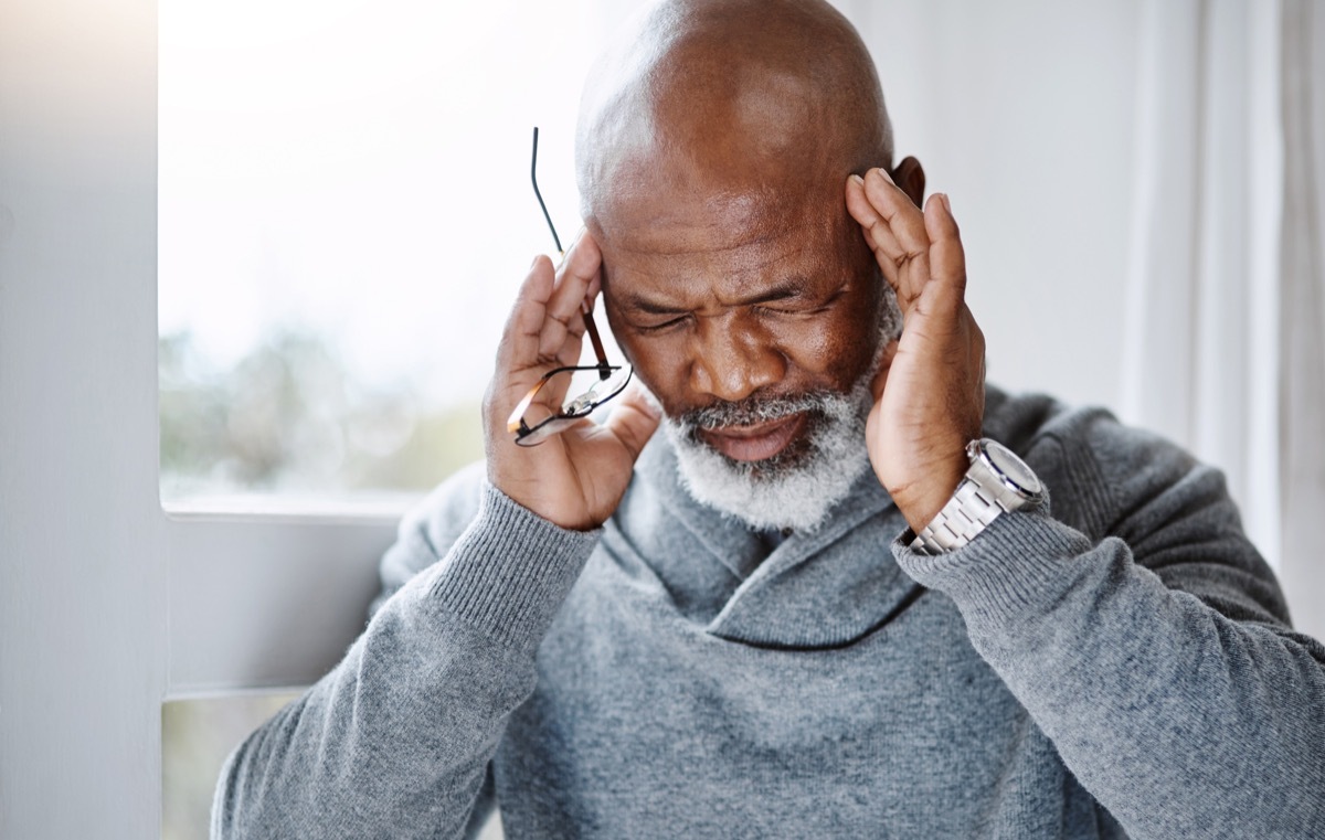 Shot of a senior man suffering with a headache at home and looking stressed out