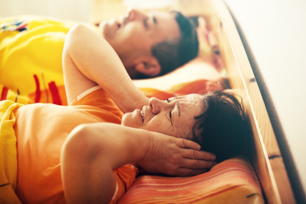 Woman Covering Her Ears Because Her Husband is snoring, signs you need a new mattress