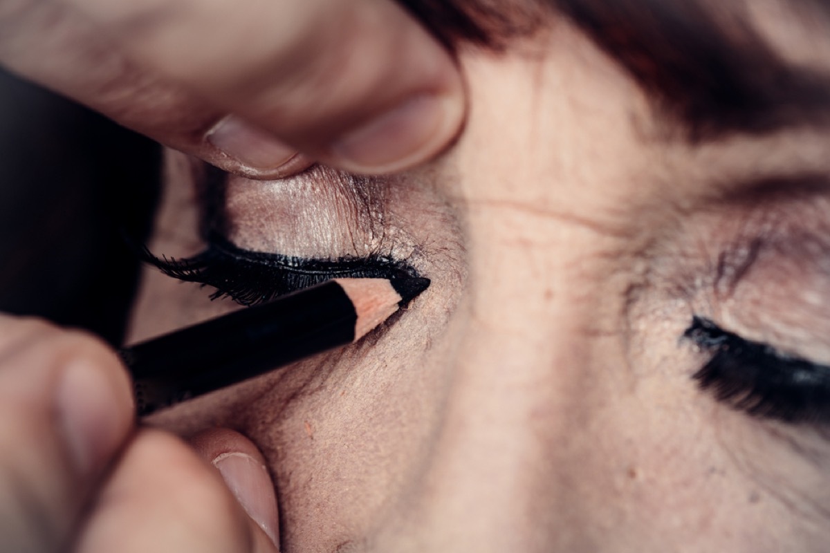 older woman applying eye makeup, look better after 40