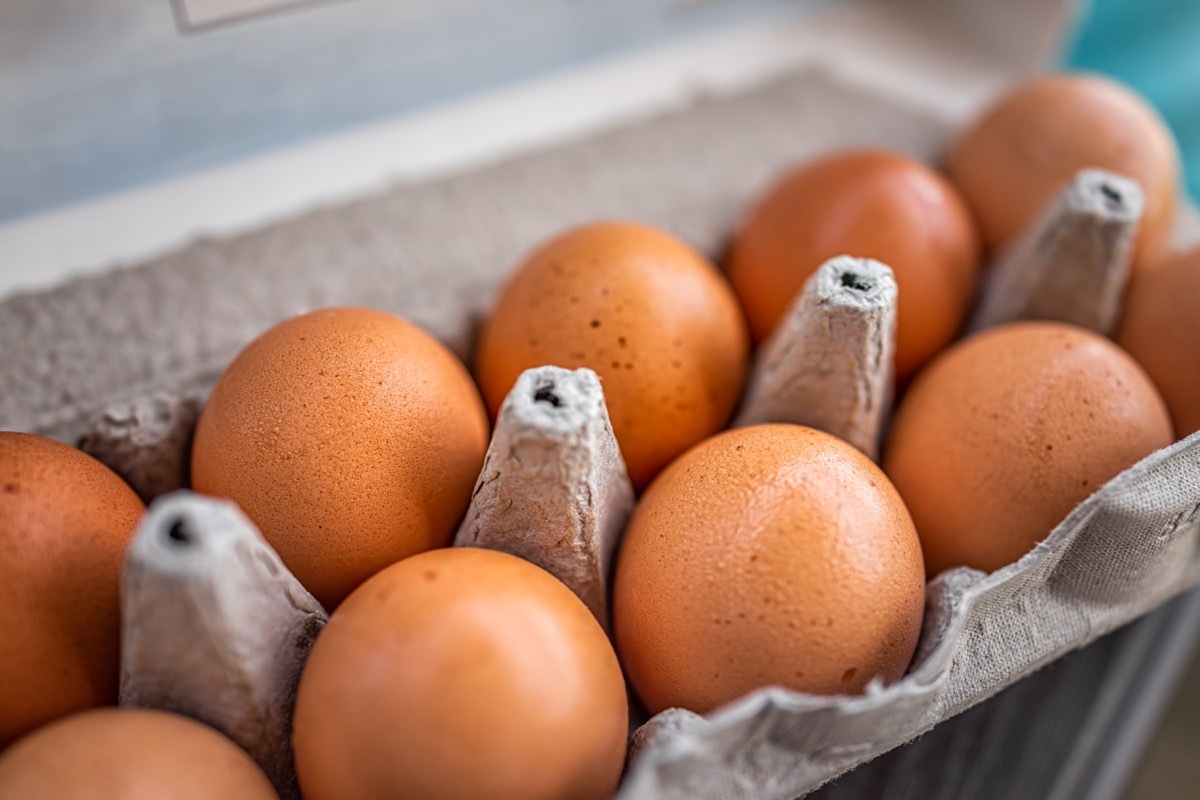 Closeup macro of pasture raised farm fresh dozen brown eggs store bought from farmer in carton box container with speckled eggshells texture