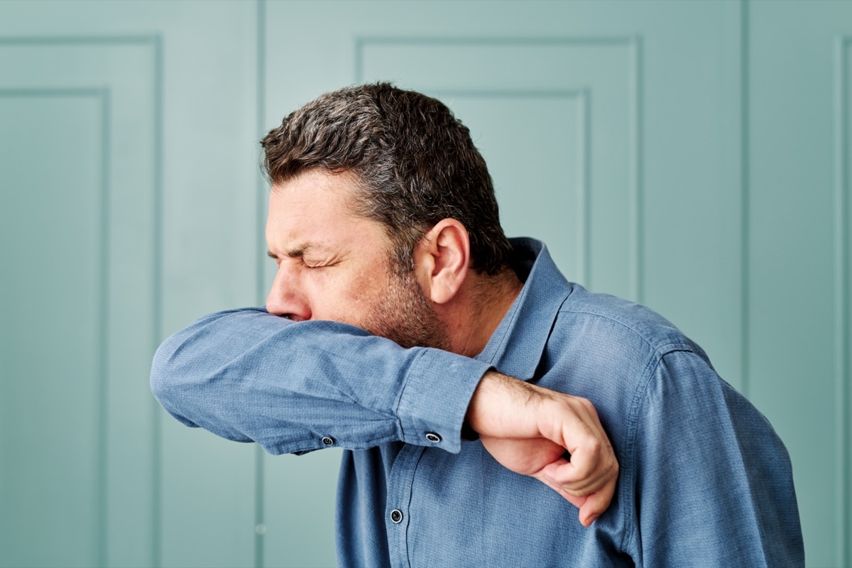 Man sneezing into his elbow.