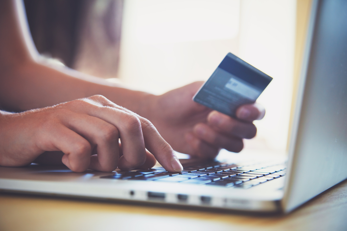 Hands holding credit card and using laptop