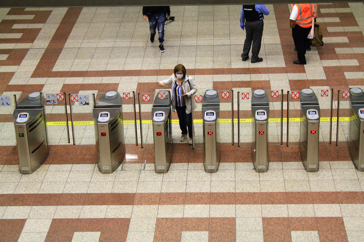 A woman woman wearing a mask enters a subway turnstile