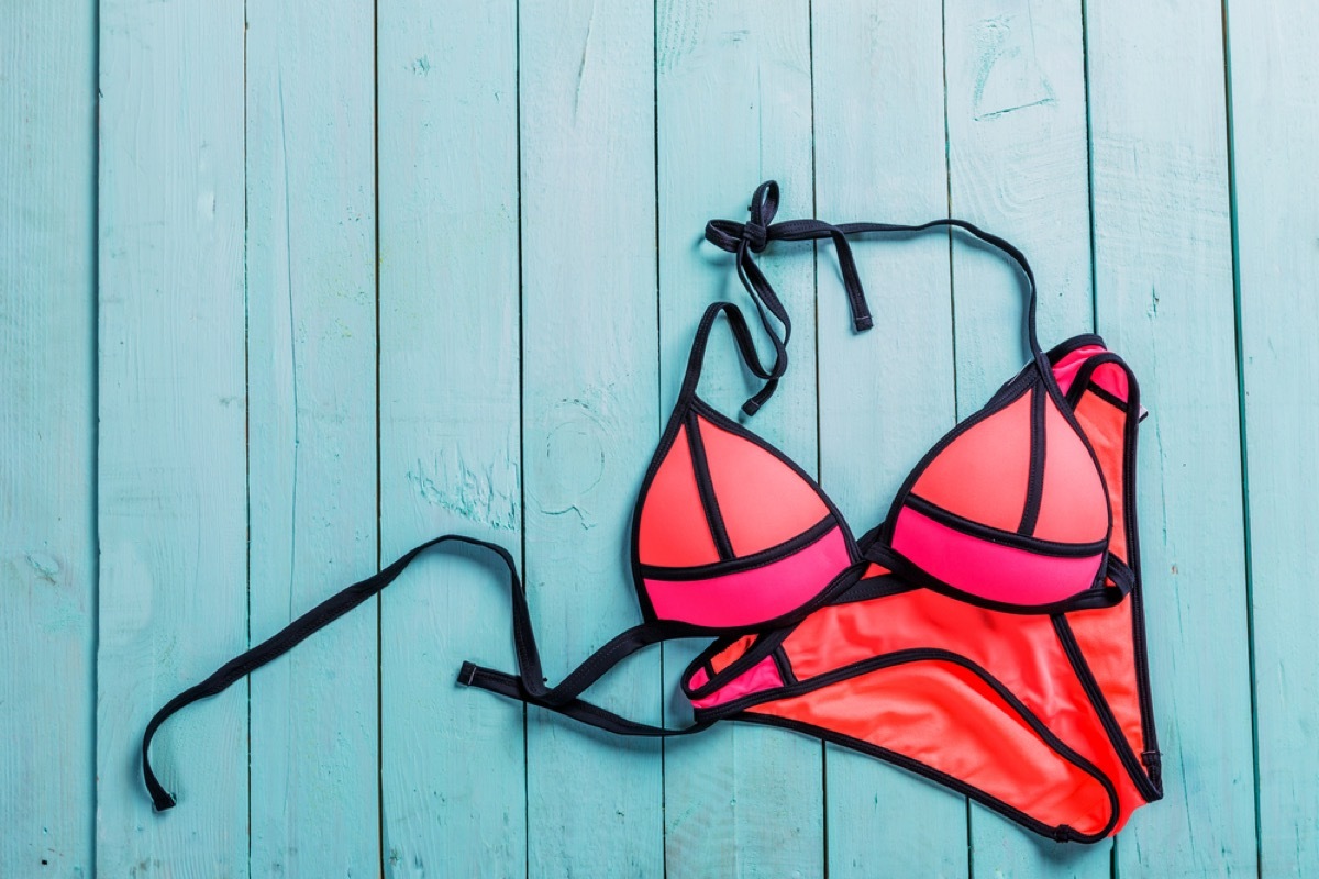 neon bikini with black outline sits on blue wooden boardwalk