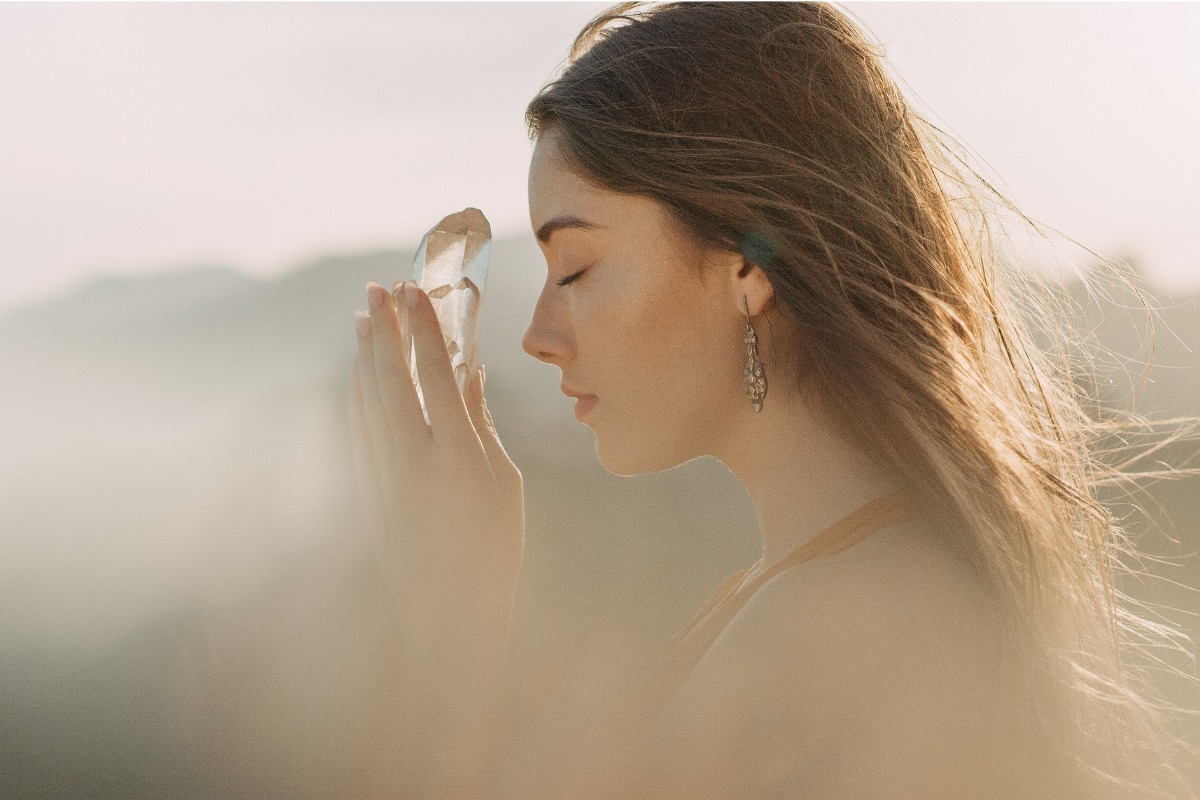 beautiful woman meditating with crystal