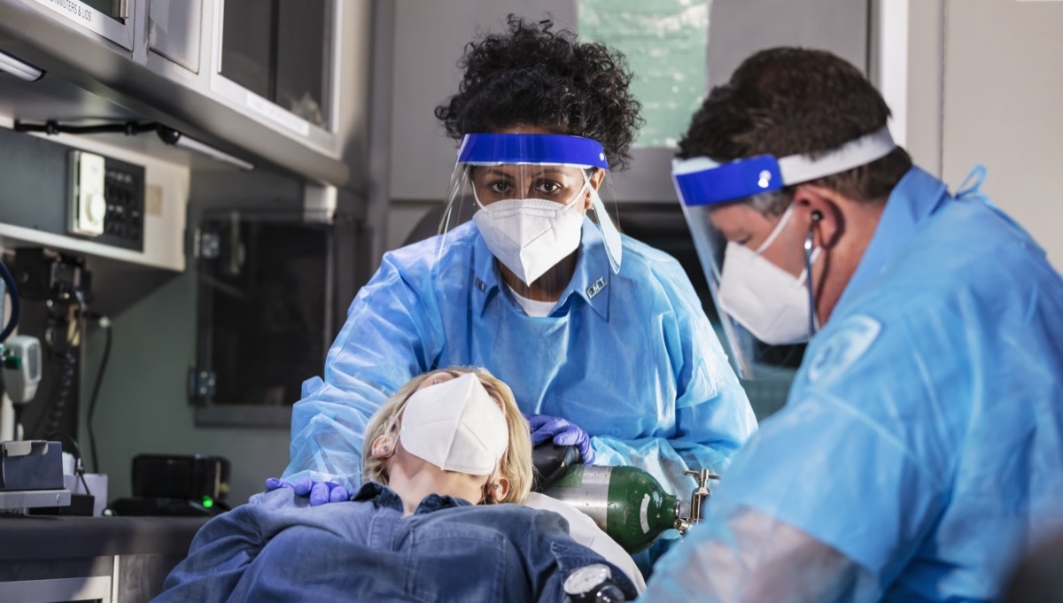 Patient in ambulance with paramedics, wearing face masks