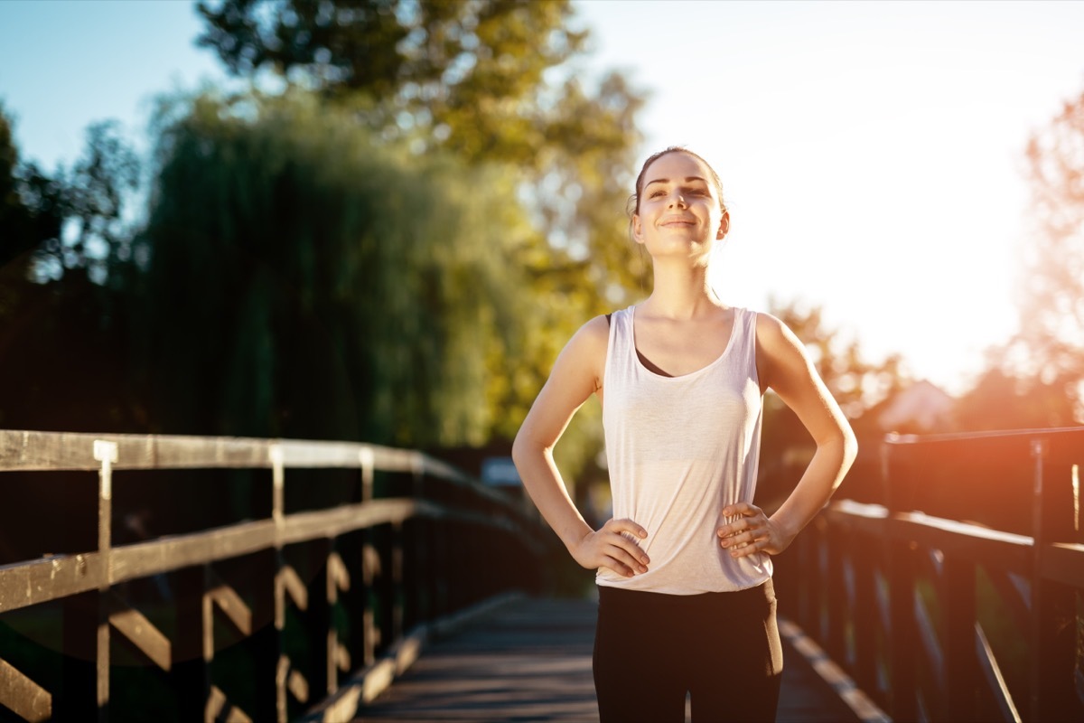 Sporty woman standing outside in the sunshine getting healthy