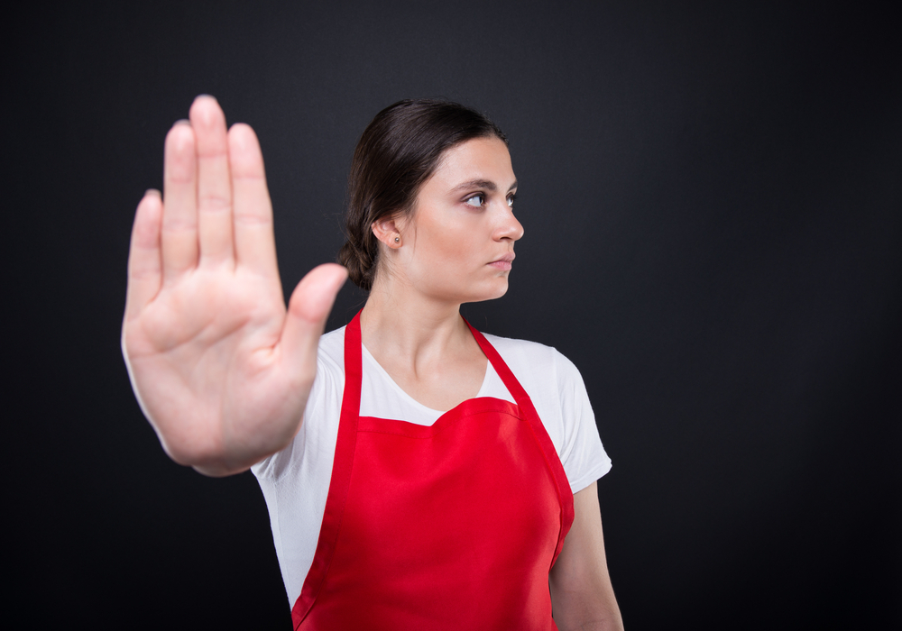 A young annoyed white female giving talk to hand gesture with palm outward