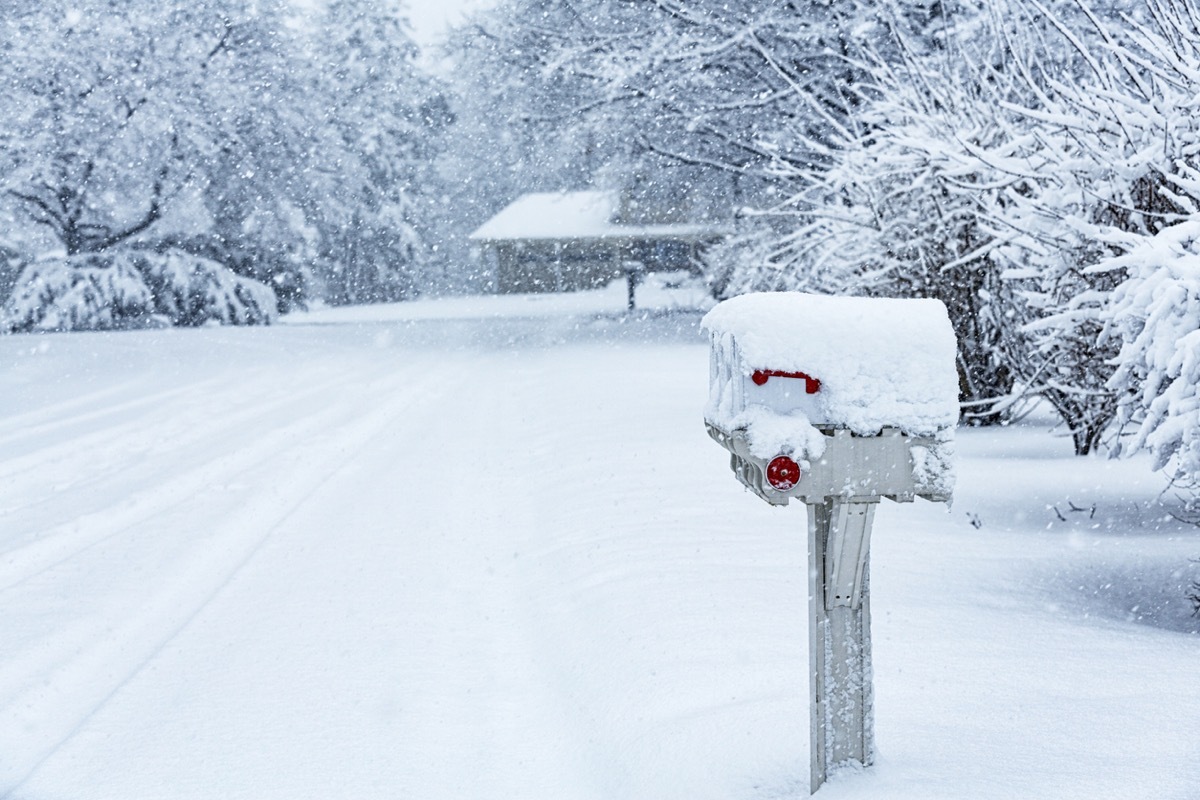 Blinding blizzard snow storm RFD (rural free delivery) roadside mailboxes on a quiet residential district street.