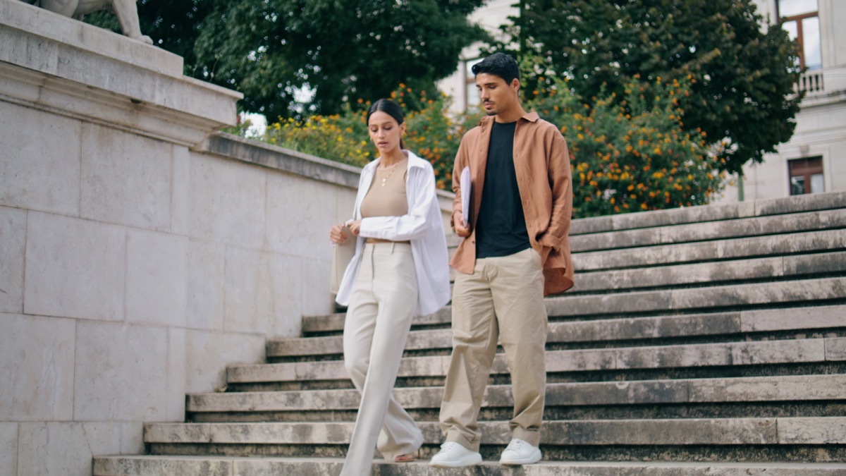 Business couple walking stairs at work break. Relaxed colleagues talking on way