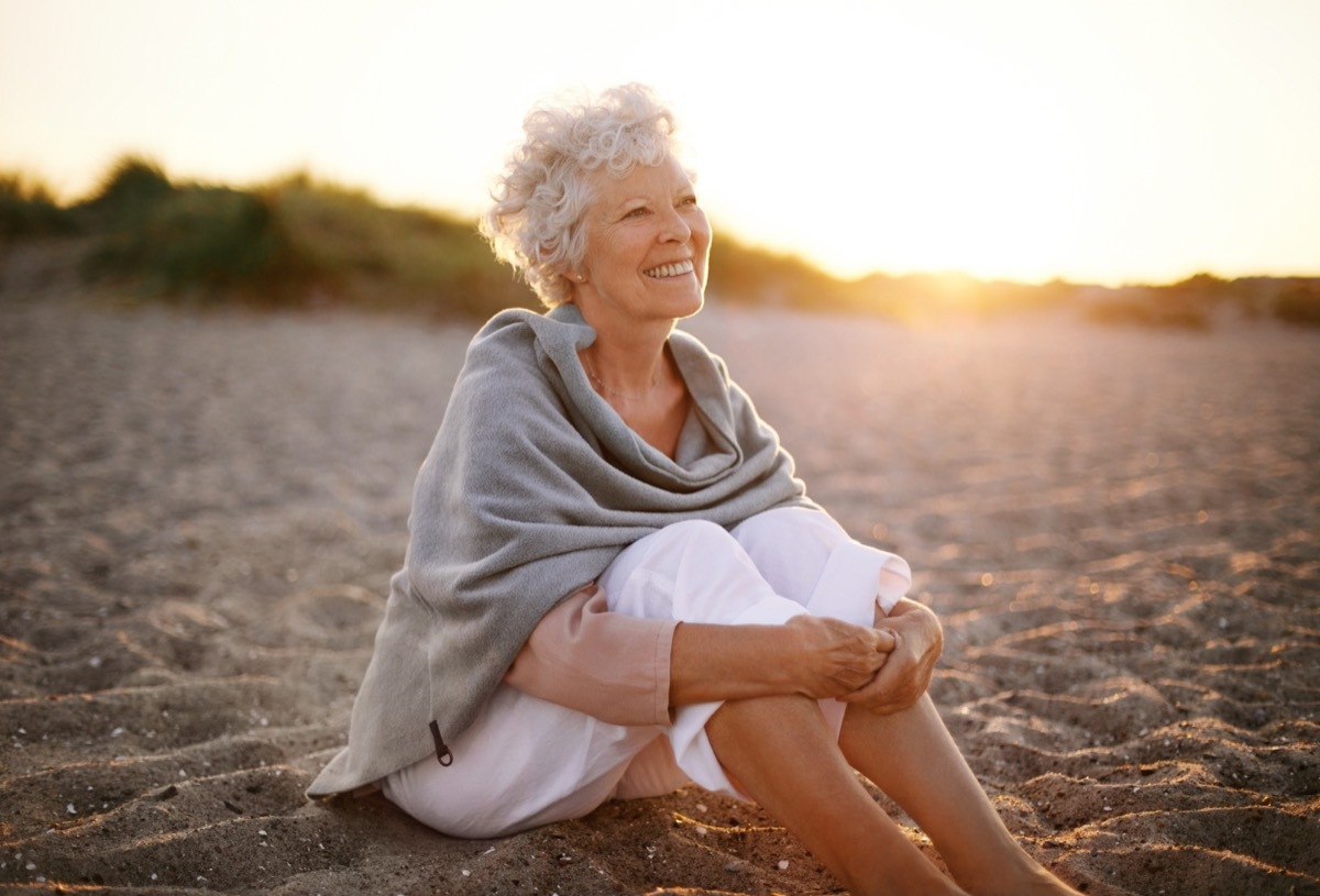 Woman sitting on beach happy. 