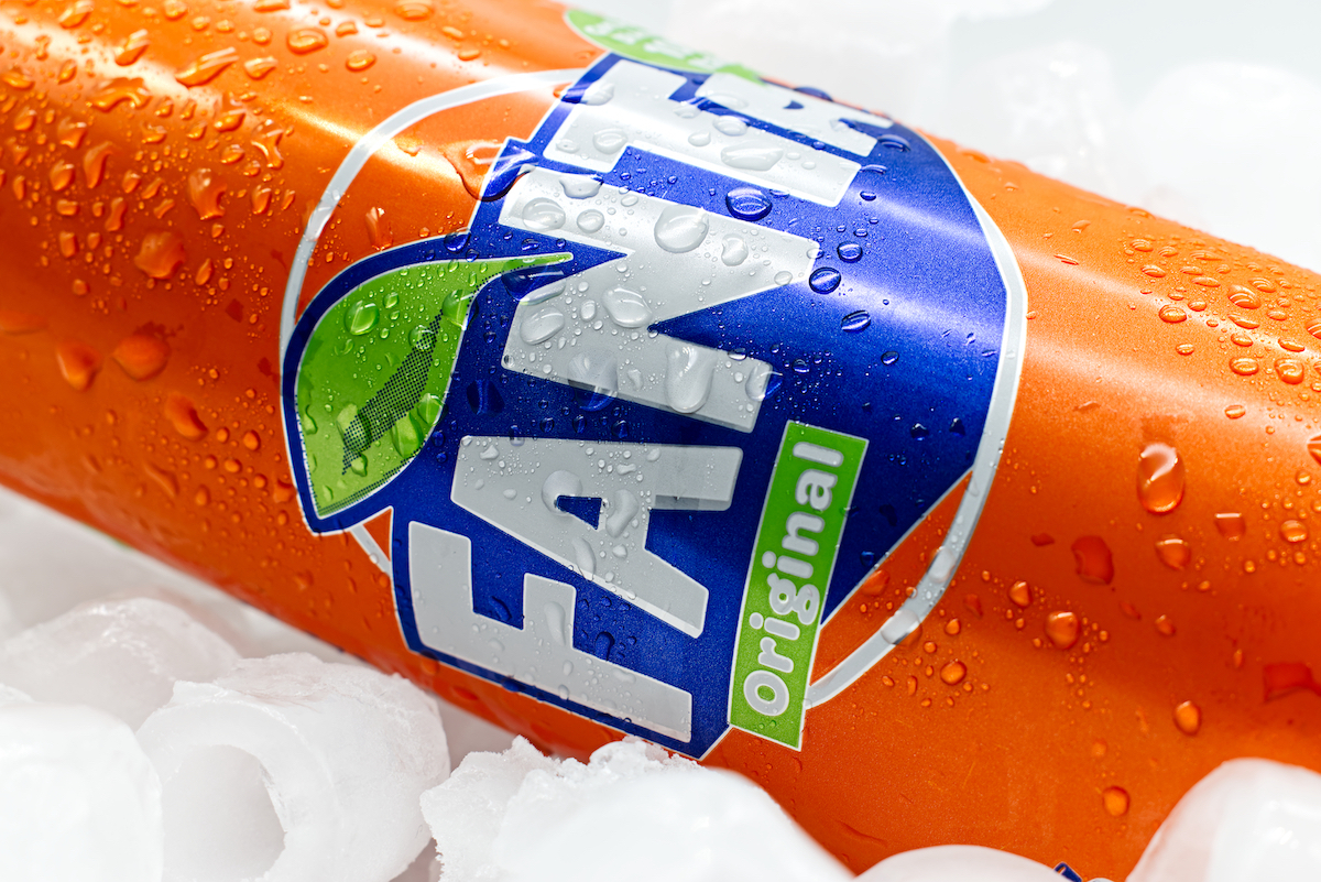 Close up of a can of Fanta orange soda on ice.