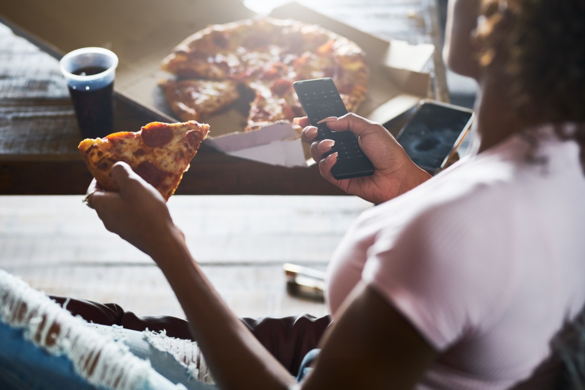 woman staying up late relaxing at home watching tv and eating pizza