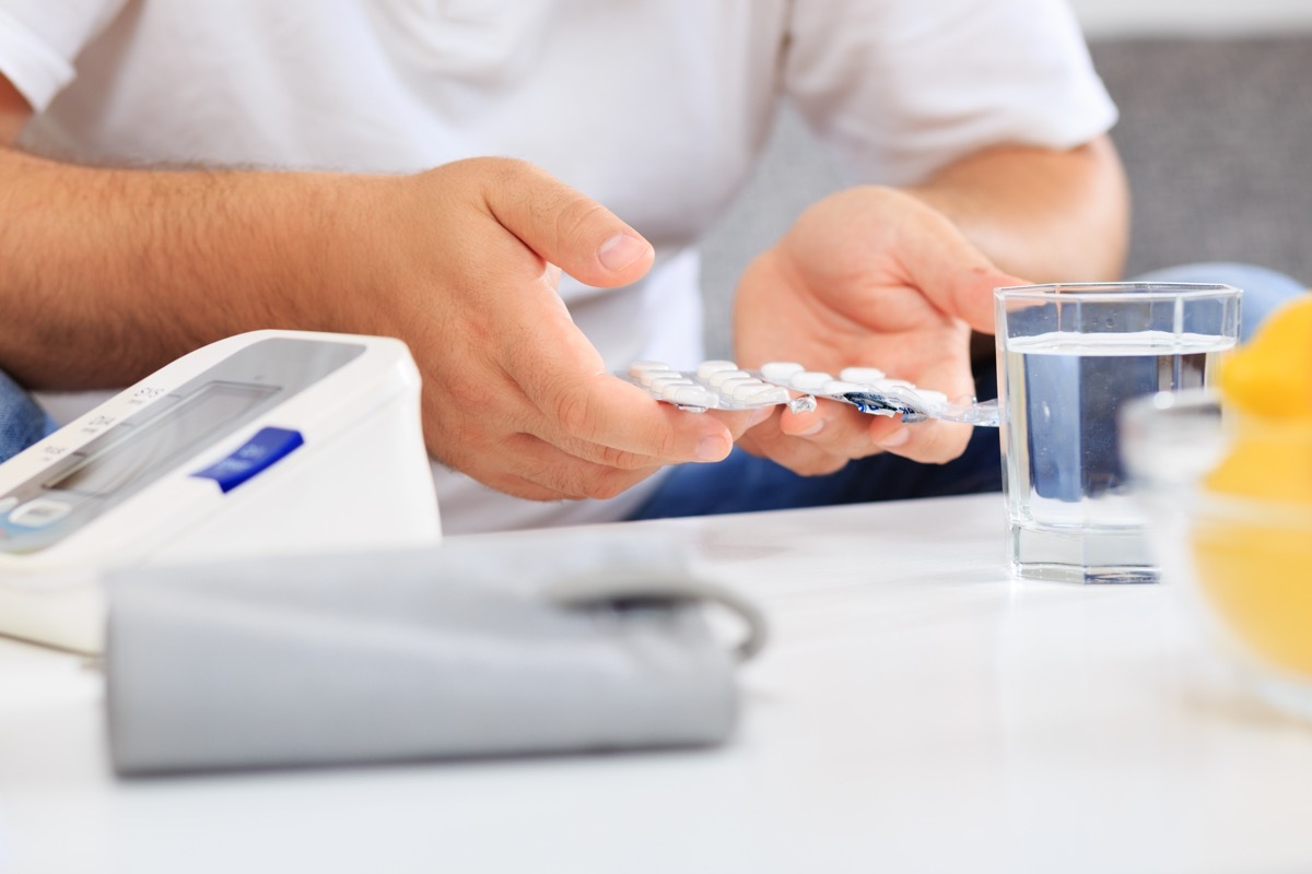 man preparing to take medication after blood pressure measuring