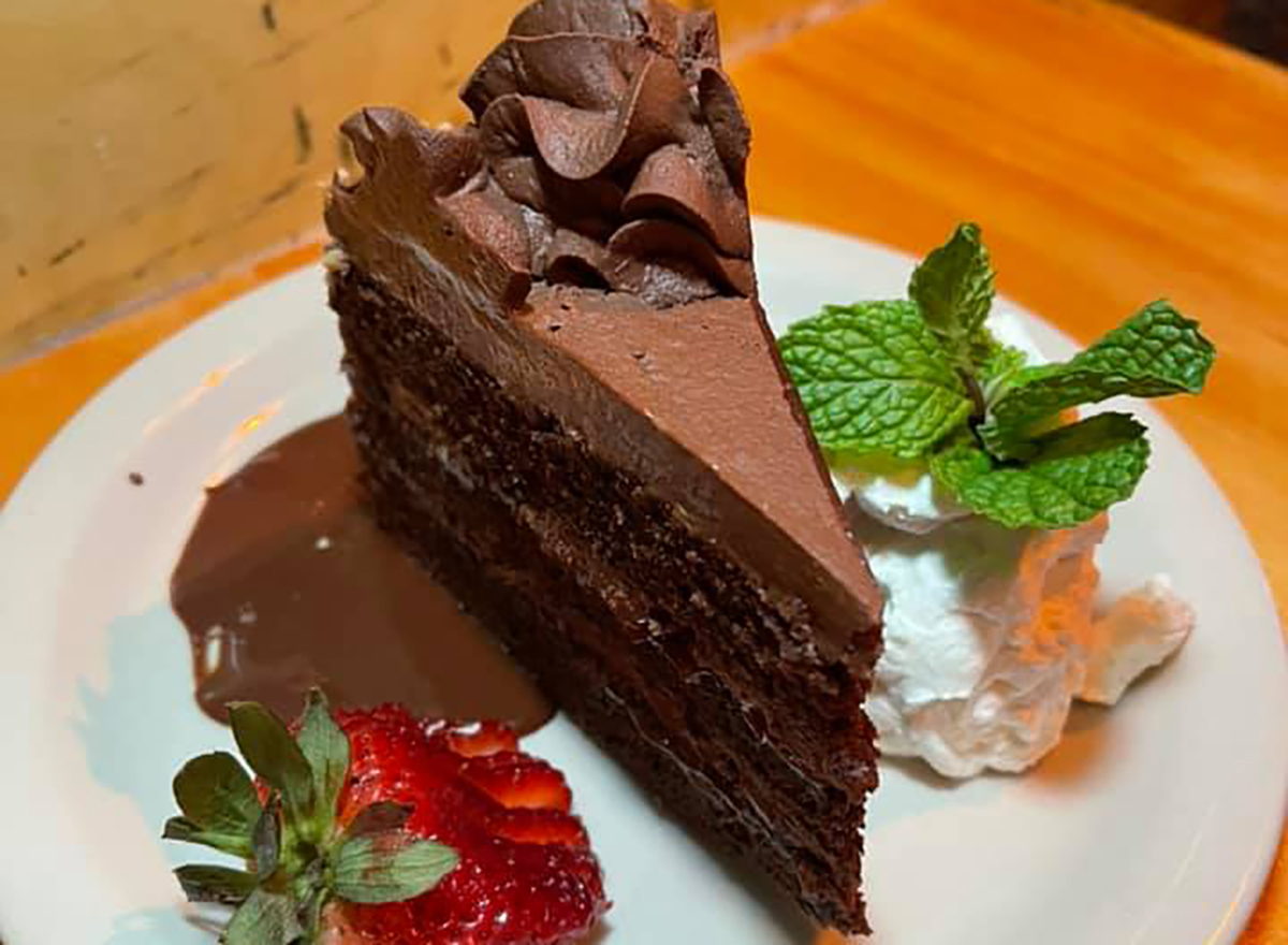 slice of chocolate layered cake with strawberry and whipped cream