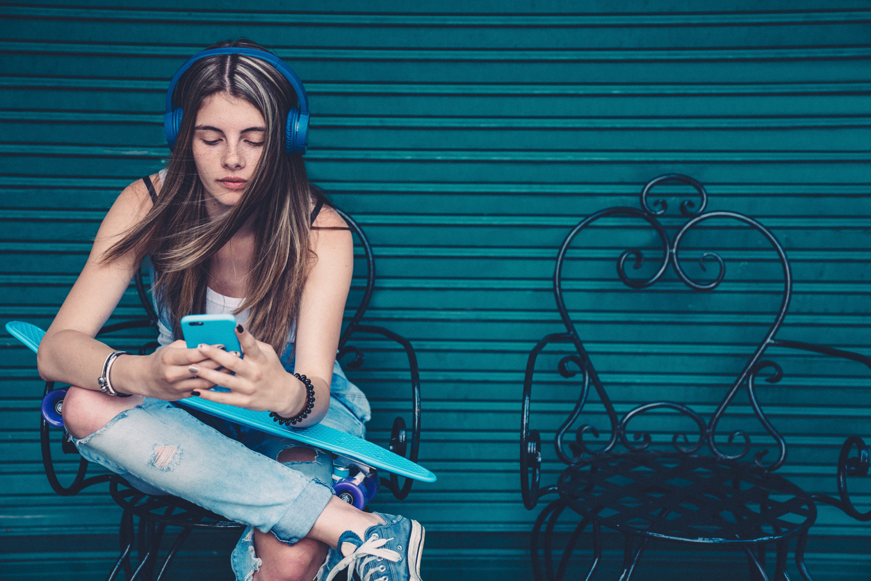 young teen with skateboard listening to music