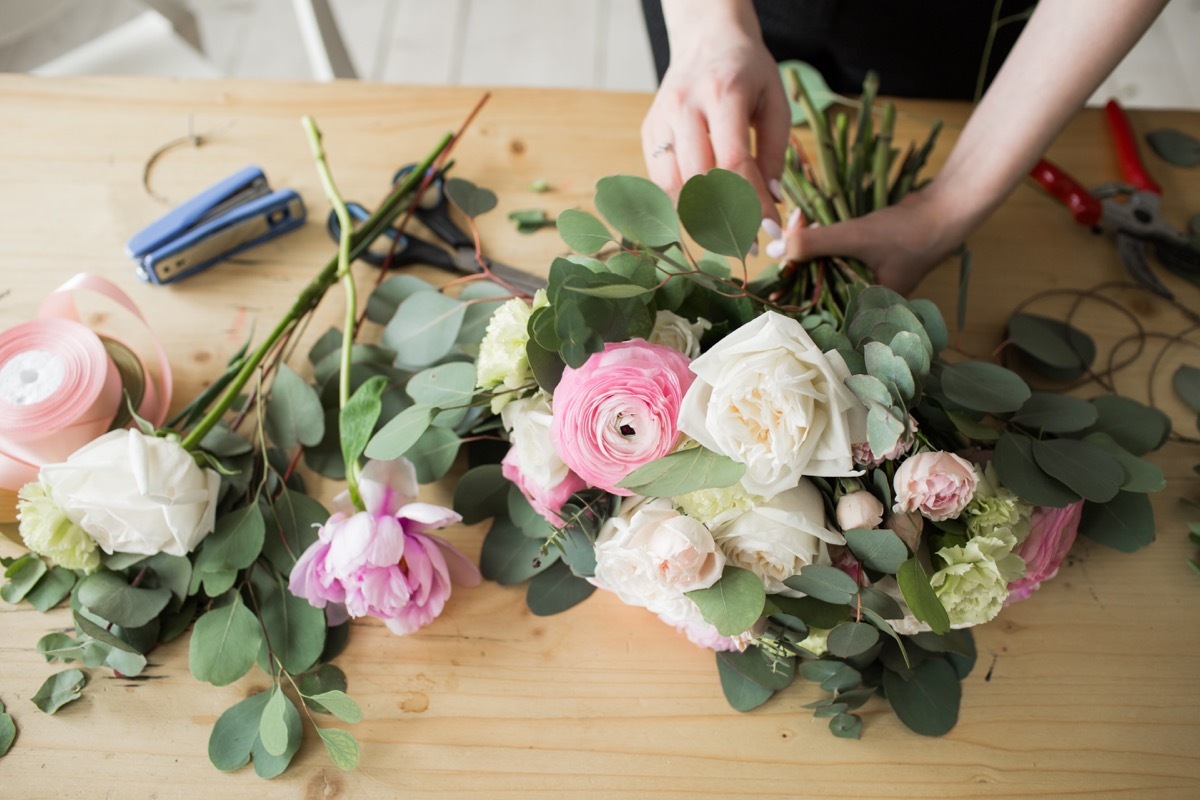 Florist at work: pretty young woman making fashion modern bouquet of different flowers.