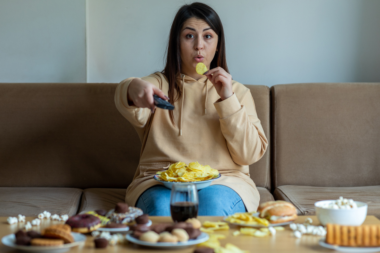 young woman enjoying junk food on the couch