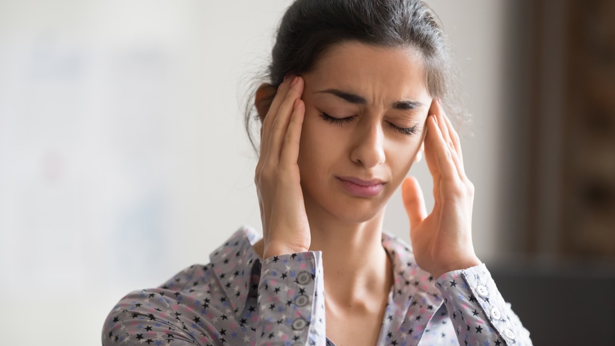 Woman rubbing her temples with headache and dizziness