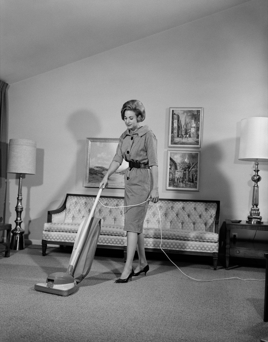 1960s white woman vacuums living room, shows how different parenting was in the 1950s