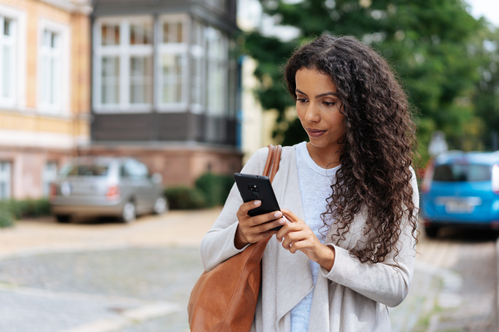 A young woman using her phone while walking down the street