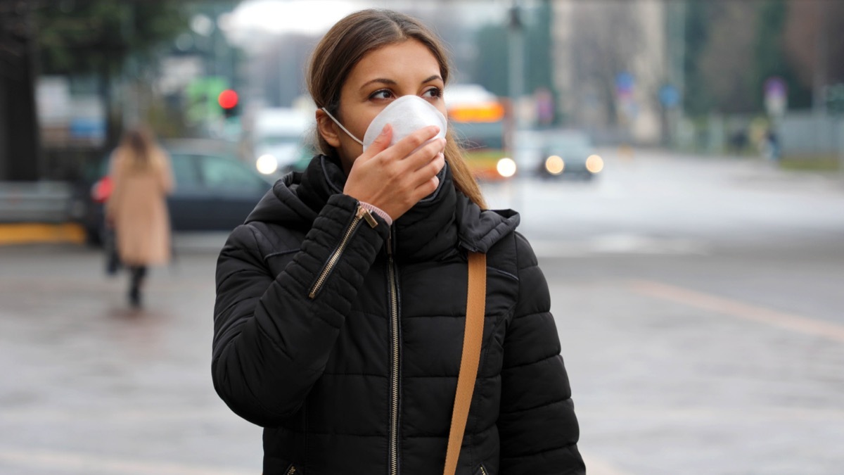 Woman on a street wearing face mask protective for spreading of disease virus SARS-CoV-2