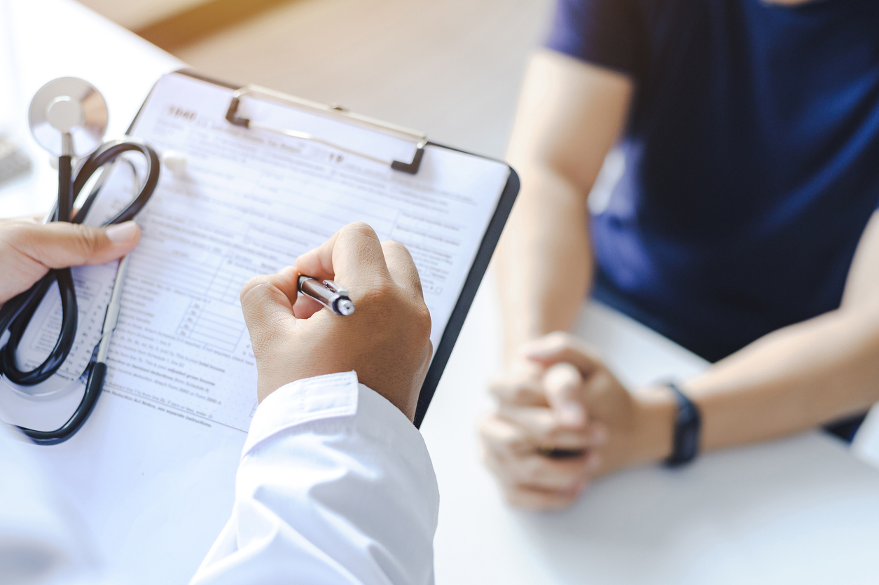 Doctor seeing a patient and writing on a medical chart.