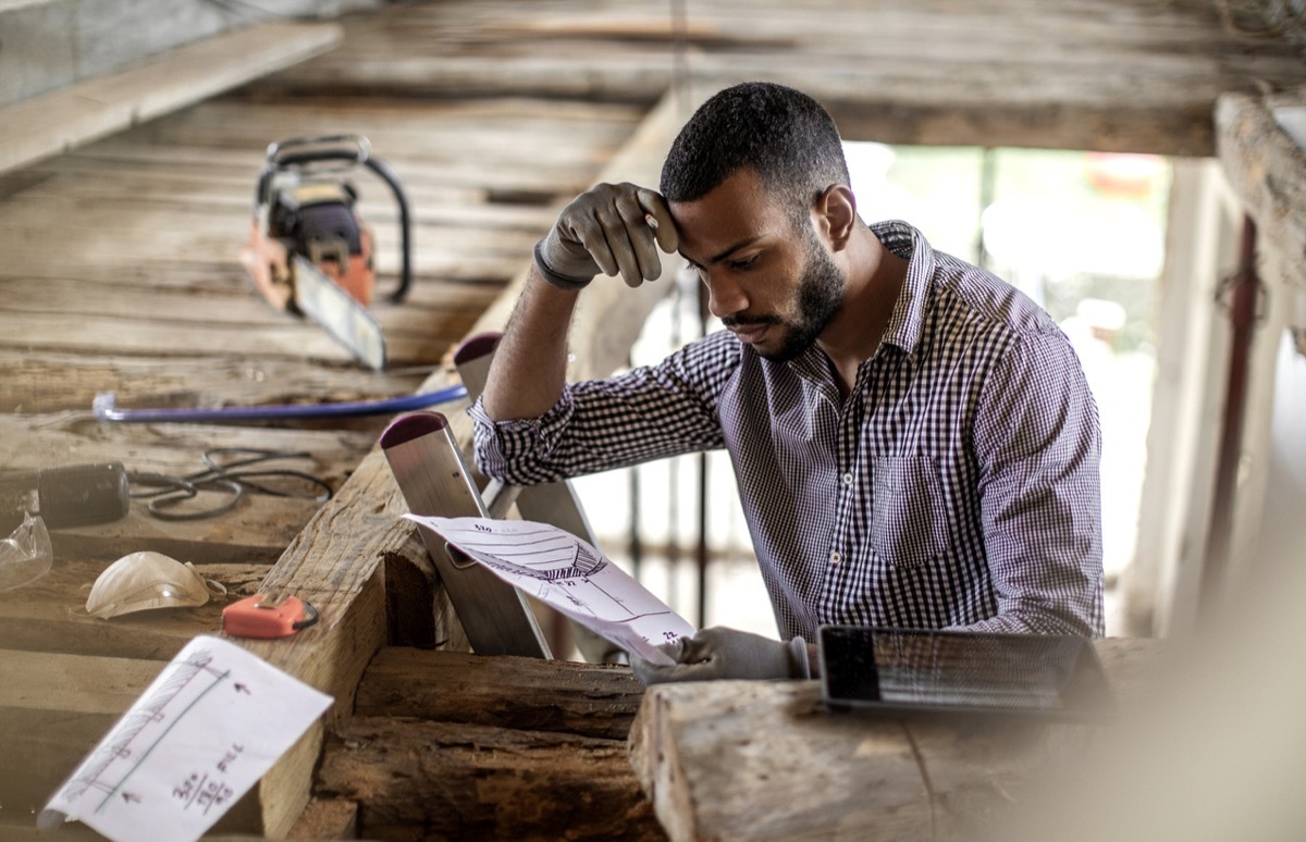 young black man looking at instructions as he renovates attic