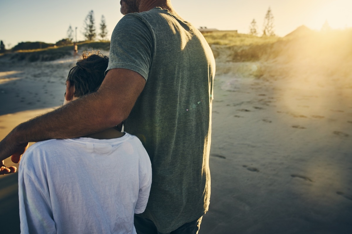 father and child walking on the beach arm and arm