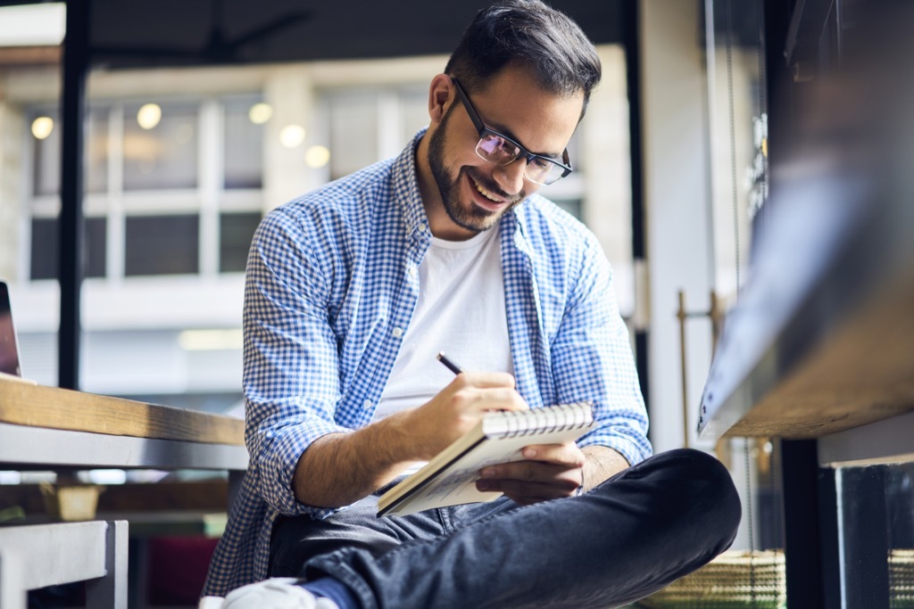 man writing in notebook