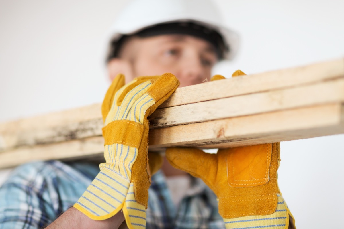 construction worker carrying wooden board