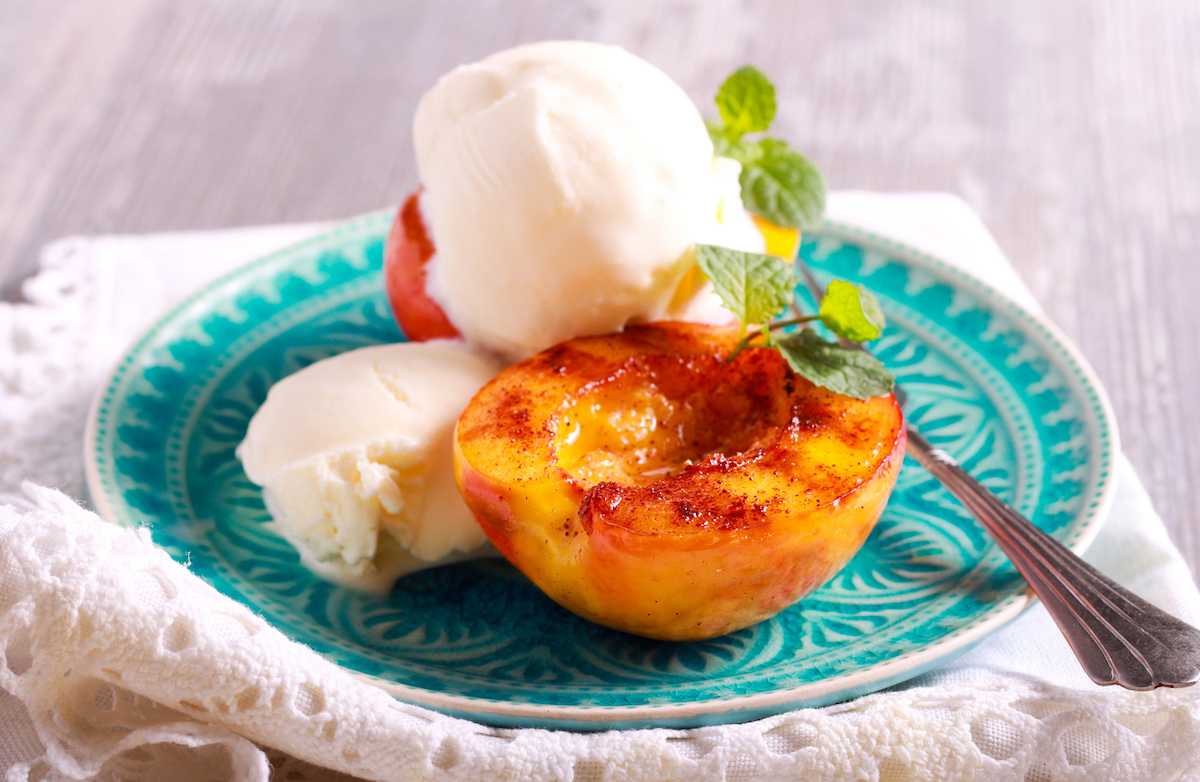 Grilled peaches and ice cream dessert over blue plate