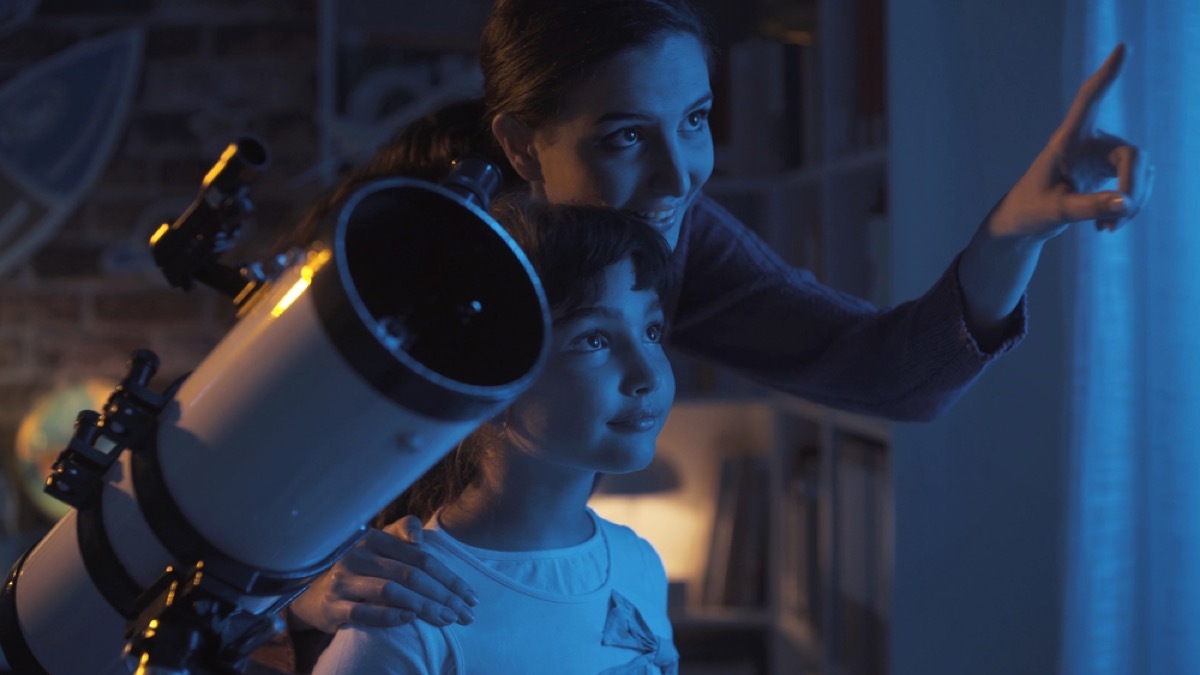 girls in bedroom with a telescope looking out window