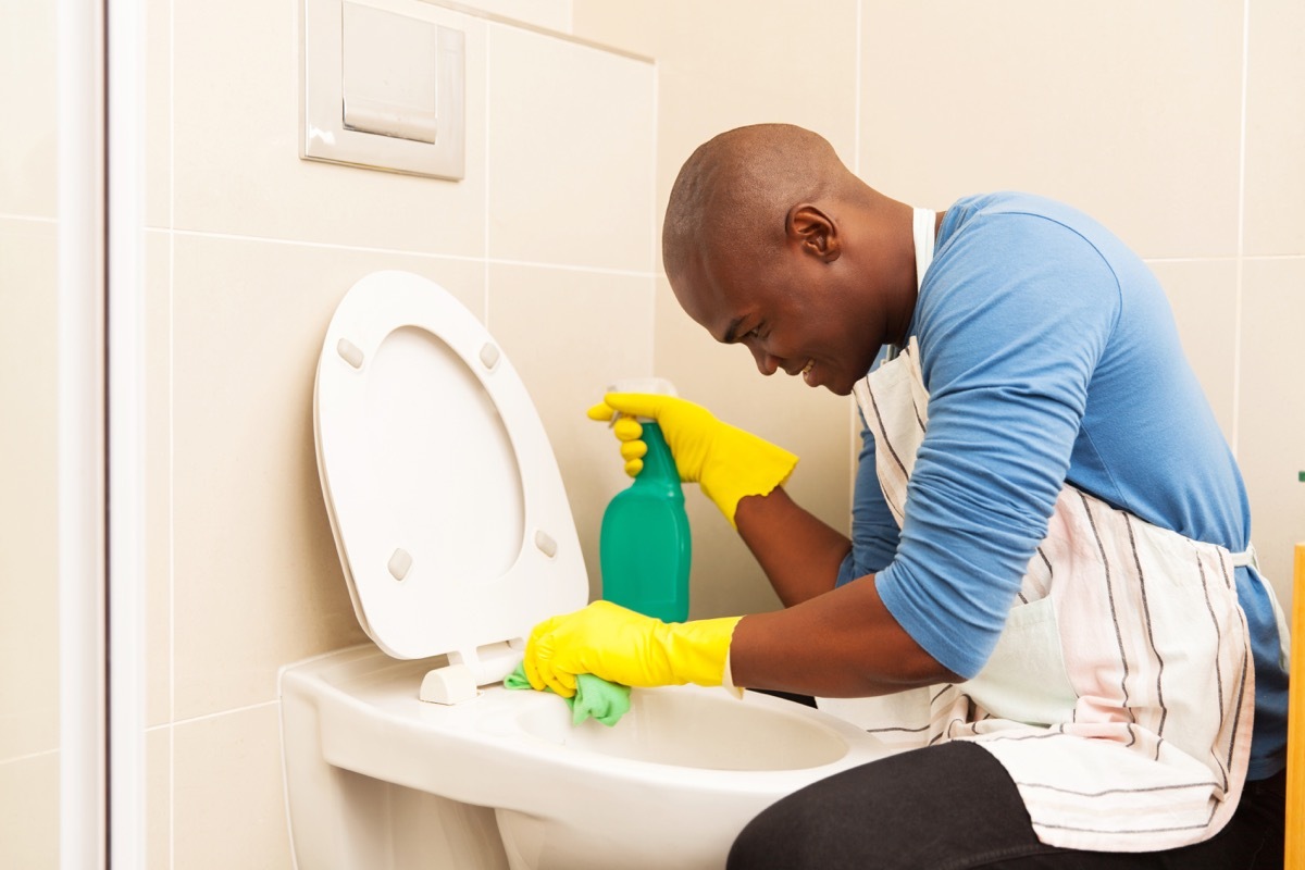 Man cleaning toilet with spray