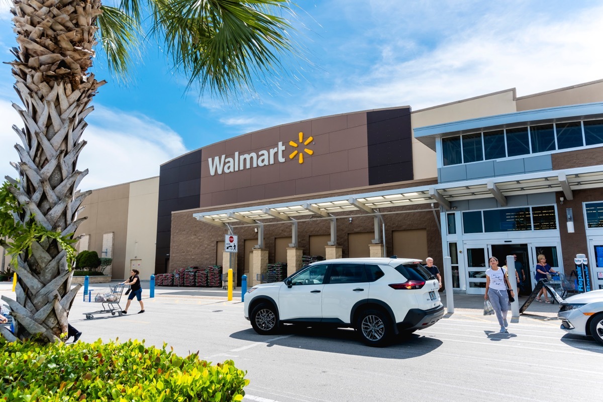 the outside of a Walmart store with customers walking out and a palm tree