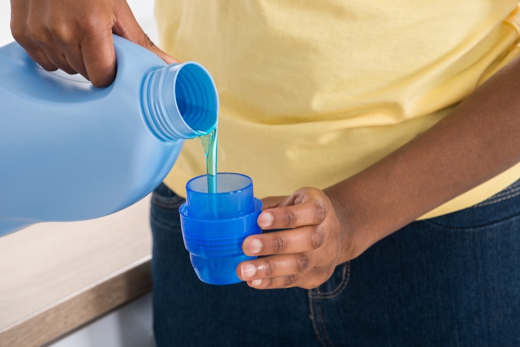 man pouring laundry detergent