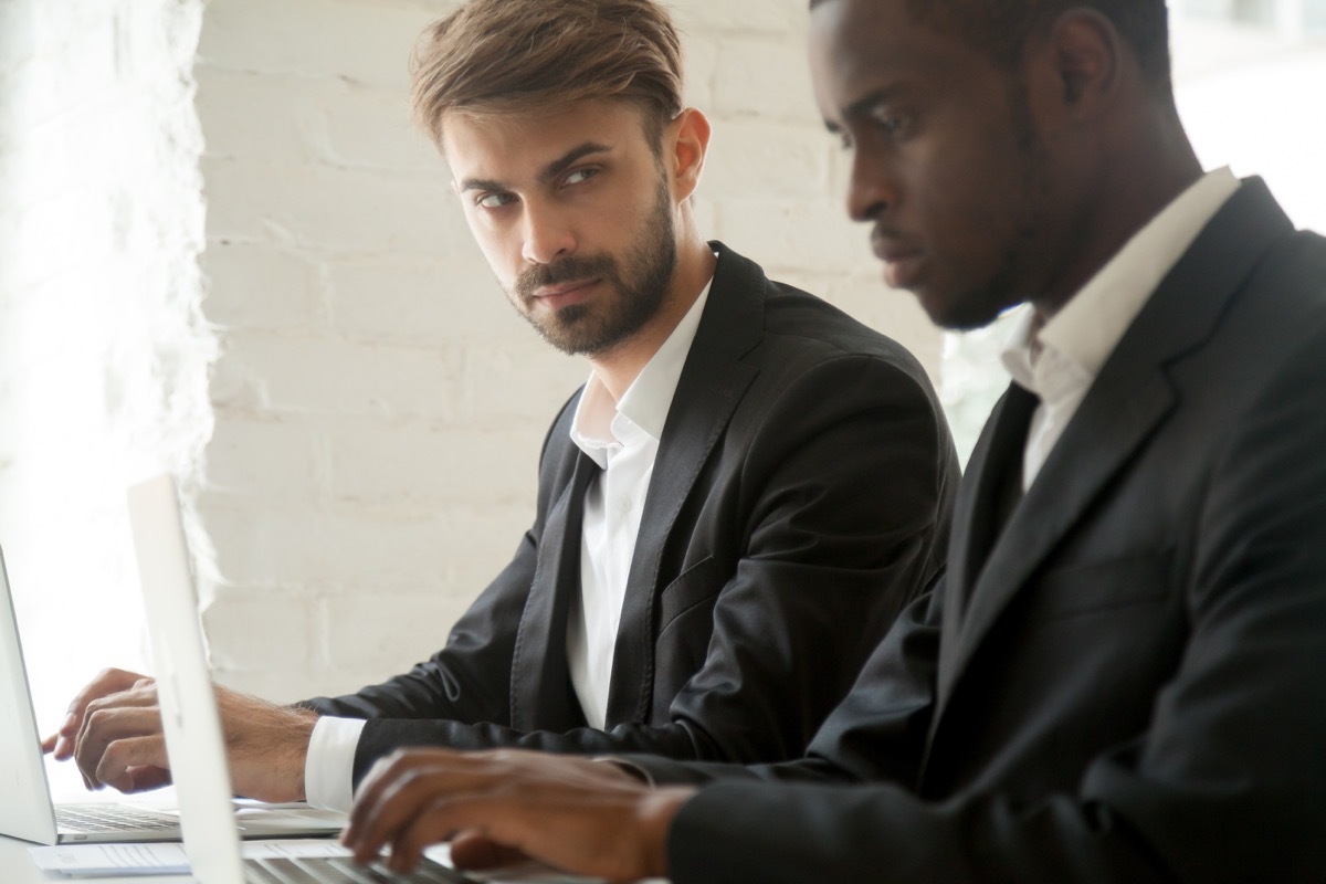 Jealous Male Coworker Looking at a Fellow Employee Things He Won't Admit