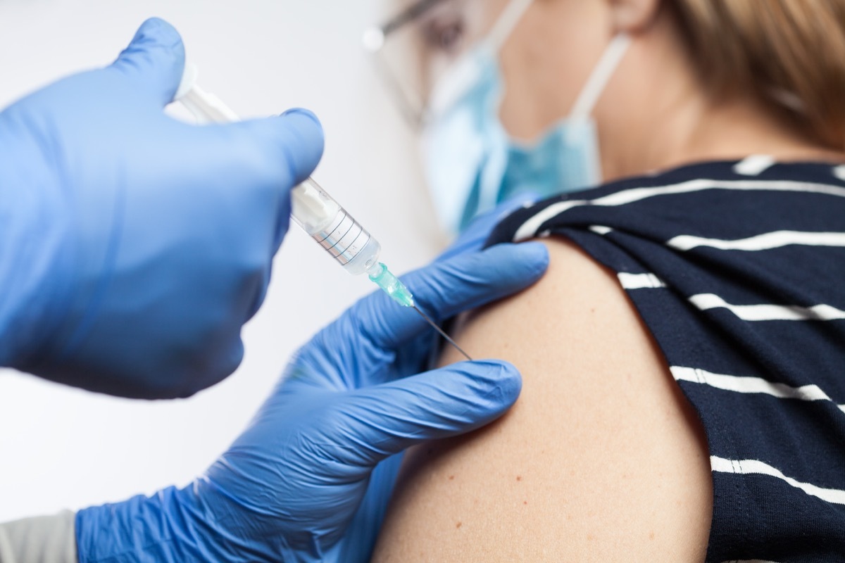 Closeup of medical worker's hands in blue protective gloves injecting vaccine booster shot into elderly patient's shoulder,Coronavirus vaccination against COVID-19 virus disease,immunity certificate