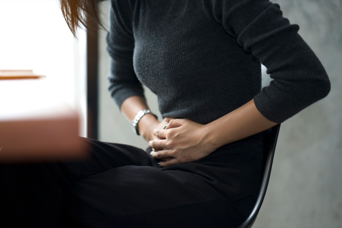 woman feeling painful from stomachache illness during working at office, hands touching her stomach and awareness of her Appendicitis sickness