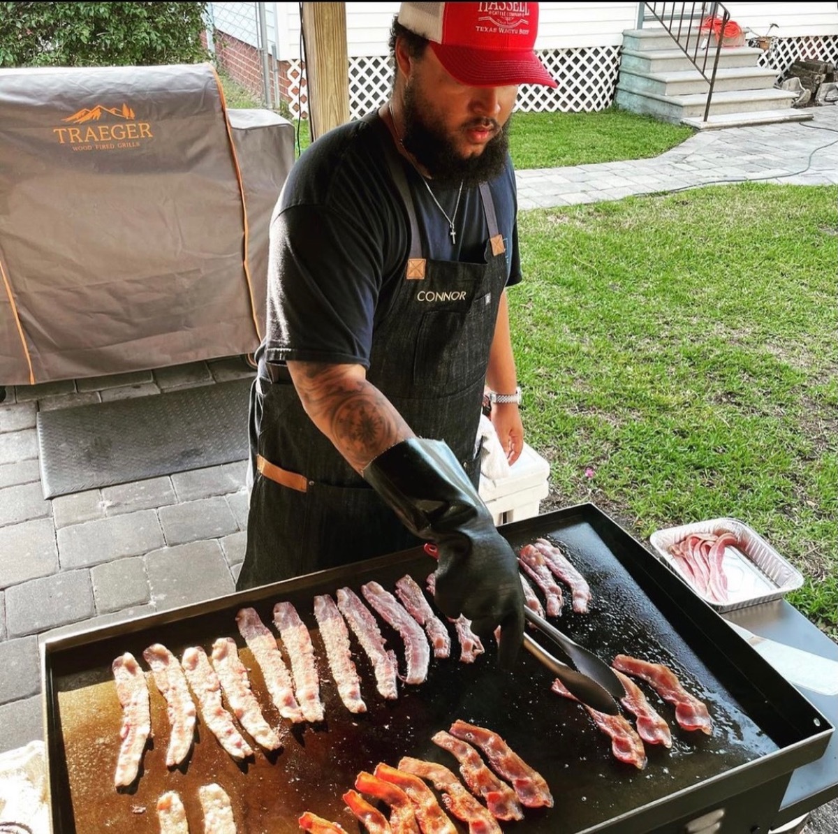 connor cruise in red and white hat grilling meat