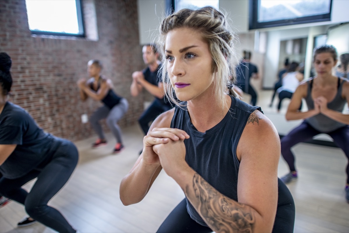 Diverse group of young adults doing squats in unison during a fitness class